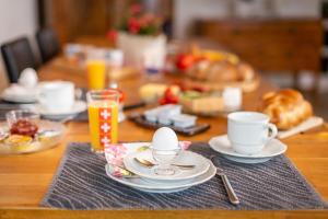 un tavolo in legno con tazze, piattini e tazze di caffè di MyBednBreakfast in Bottmingen a Bottmingen