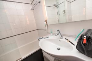 La salle de bains est pourvue d'un lavabo, d'un miroir et d'une baignoire. dans l'établissement Ibis Styles Paris Massena Olympiades, à Paris