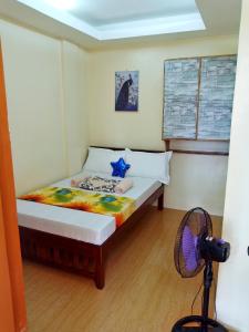 uma pequena cama num quarto com uma ventoinha em Aquing's Place em El Nido