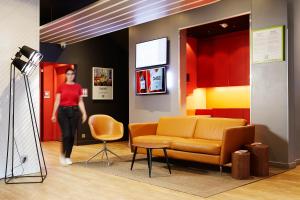 a woman walking through a room with a couch and chairs at Ibis Styles Paris Massena Olympiades in Paris
