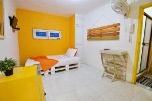 a yellow room with a bed and a desk at QuillaHost Guesthouse in Barranquilla