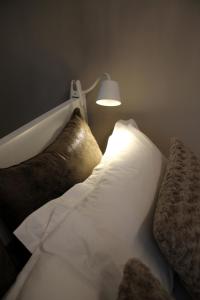 ラ・マドレーヌにあるNew West Roomのベッド1台(枕2つ、壁にランプ付)