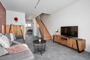 ein Wohnzimmer mit einem Sofa und einem Flachbild-TV in der Unterkunft Boutique Apartments Kirchzarten in Kirchzarten