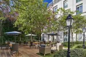 een houten terras met stoelen, tafels en parasols bij Hotel Vacances Bleues Villa Modigliani in Parijs