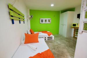 Habitación verde con 2 camas y almohadas de color naranja en QuillaHost Guesthouse, en Barranquilla
