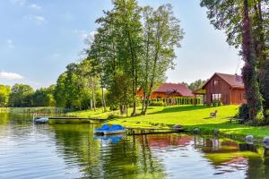 a boat is docked on a river with a barn at Latkrantė in Latežeris