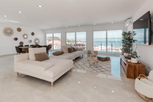 uma sala de estar com mobiliário branco e vista para o oceano em La villa Rêve d été na Lourinhã