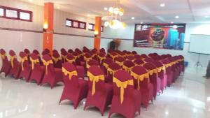 una sala conferenze con sedie rosse con fiocchi gialli di Hotel Surya Utama - Syariah a Probolinggo
