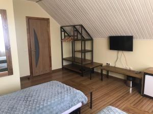 a bedroom with a bed and a desk and a television at Sadyba DarKa in Ternopilʼ