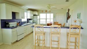 een keuken met witte kasten en barkrukken bij Spacious Galveston Retreat with Yard and Beach Access! in Galveston