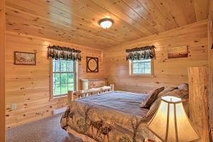 a bedroom with a bed in a log cabin at Rustic Benezette Cabin with Porch, Hot Tub and Fire Pit in Benezette