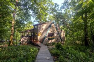 a tiny house in the woods with a wooden walkway at Dock and Resort Perks Quiet Lakefront Cottage in Innsbrook