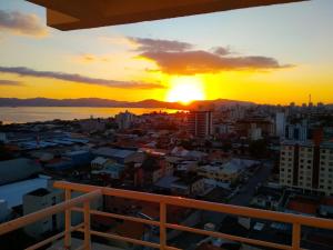 einen Blick auf den Sonnenuntergang vom Balkon einer Stadt in der Unterkunft Ap em São José com linda vista para o mar in São José