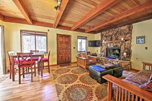 a living room with a table and a stone fireplace at Big Bear Cabin with Fenced Yard 4 Mi to Snow Summit in Big Bear City