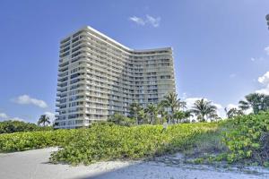 a tall building with palm trees in front of a beach at Resort Condo with Balcony and Stunning Ocean Views! in Marco Island