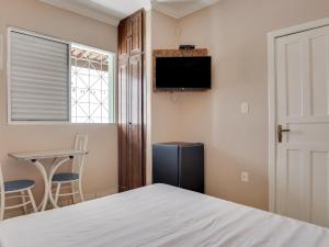 a bedroom with a bed and a tv and a table at Hotel Estrela Do Vale in Ipatinga