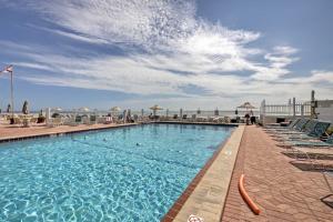 a large swimming pool with chairs and acean gmaxwell gmaxwell gmaxwellzos at Daytona Beach Studio with Oceanfront Balcony and Pool! in Daytona Beach