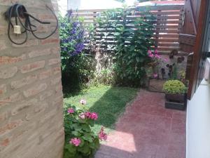 un jardín con flores rosas y una valla en Duplex Vivero Miramar Argentina en Miramar