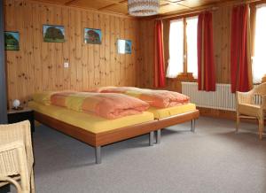 2 letti in una camera con pareti in legno e tende rosse di Bühlerhof a Lenk