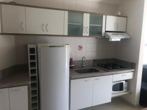 eine Küche mit weißen Schränken und einem Kühlschrank in der Unterkunft Enseada Nautico Residence in Caldas Novas