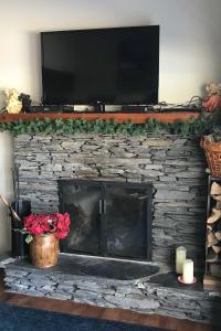 a stone fireplace with a television on top of it at Stowe Vacation Rental with Deck and Mountain Views! in Stowe