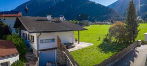 a small white house with a green field and mountains at Ahorn Chalet in Mayrhofen