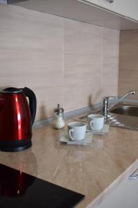 a kitchen counter with two cups and a sink at Apartmani 23 in Novi Pazar