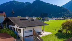 una casa en un campo con montañas en el fondo en Ahorn Chalet, en Mayrhofen