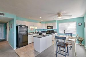 a kitchen with white cabinets and a black refrigerator at Beachfront Cedar Key Condo with Pool, Spa and Views! in Cedar Key