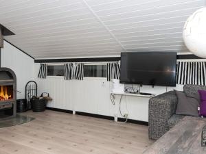 een woonkamer met een tv, een bank en een open haard bij Vibrant Holiday Home in Syddanmark with Barbecue in Toftlund