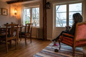 a woman sitting in a chair looking out a window at Cottage - Majviken in Ljungskile