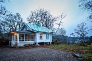 uma pequena casa branca com um telhado verde em Cottage - Majviken em Ljungskile