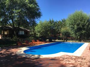 a swimming pool in a yard with chairs and trees at Cabañas Los Maderos in Villa General Belgrano