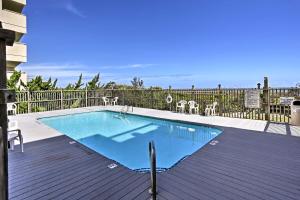 a swimming pool with tables and chairs on a deck at Ocean-View Condo with Deck, Steps to Carolina Beach! in Carolina Beach