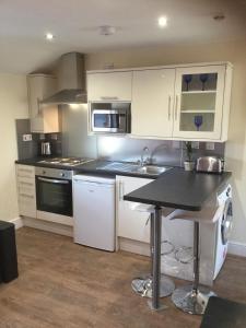uma cozinha com armários brancos e um balcão preto em Modern Luxury Central Apartment em Birmingham