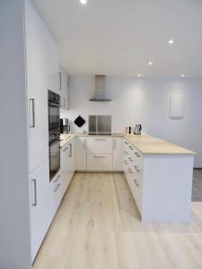 a kitchen with white cabinets and a wooden floor at New, modern apartment near the centre of Tórshavn in Tórshavn