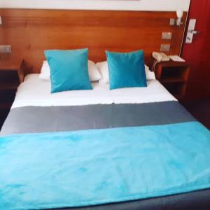 1 dormitorio con 1 cama grande con almohadas azules en Hotel Real en Linares