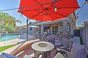d'une terrasse avec une table, des chaises et un parasol rouge. dans l'établissement Arizona Retreat with Heated Pool, Fire Pit and Grill!, à Surprise