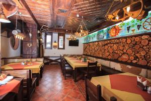 a restaurant with tables and chairs and a wall with logs at Zlaten Rozhen Family Hotel- Monument of Cultural Significance in Rozhen