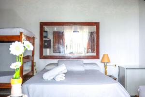 a bedroom with a bed with white sheets and a mirror at Cururupe Praia Hotel in Ilhéus