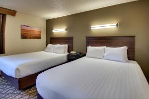 two beds in a hotel room with white sheets at EverSpring Inn in Bismarck