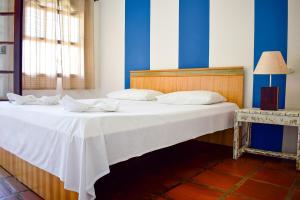 
a bed room with a white bedspread and a blue wall at Pousada Maanaim 2 in Ubatuba
