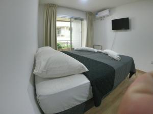 Un dormitorio con una cama con almohadas blancas y una ventana en Departamento Aires Verdes de Salta en Salta