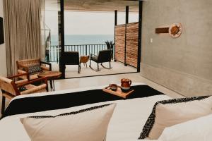 Hotel B Unique في كوزوميل: غرفة نوم مع سرير وشرفه مع المحيط