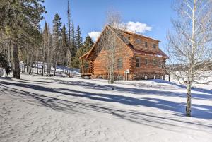 una cabaña de madera en la nieve con una carretera en Modern Cabin with Deck Near Zion National Park!, en Duck Creek Village