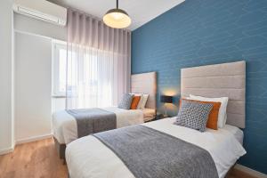 ein Schlafzimmer mit 2 Betten und einer blauen Wand in der Unterkunft Marquês Pombal Apartment in Lissabon