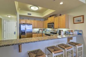 a kitchen with a counter with stools and a refrigerator at Beachfront Dauphin Island Condo with 2 Pools and Sauna in Dauphin Island