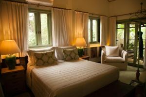 um quarto com uma cama, uma cadeira e janelas em Templo Do Ser em Ilhabela