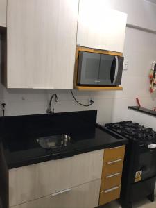 uma cozinha com um micro-ondas e um fogão em Solaris Residencial Clube 1601 de Frente Para o Mar em Ilhéus