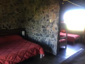 um quarto com uma cama e uma parede de pedra em San Francisco De Las Sierras em Minas